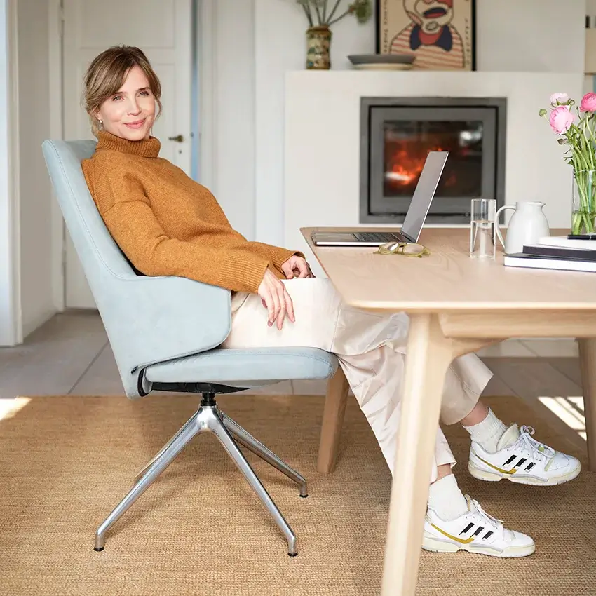 Junge Frau arbeitet mit Laptop am Esszimmertisch. Sie sitz in einem Stressless Laurel mit hoher Rückenlehne